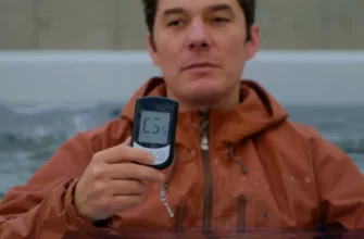 A person standing in a cold plunge tub, wearing a light jacket, holding a digital blood glucose meter, with water droplets and subtle reflections on the water surface, set in a calm, cool environment