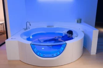 A sleek, modern cold plunge tub in a minimalist home setting, with a person stepping into it, surrounded by cool blue lighting, showcasing a high-end design, with a subtle reflection on the water surface