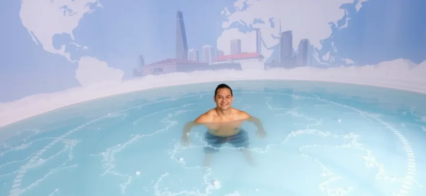A person standing in a clear, icy cold plunge pool surrounded by a subtle globe or world map backdrop, with a hint of Melbourne's skyline in the distance, capturing the global nature of cold plunging