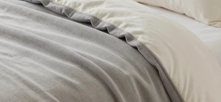 A cozy bedroom scene with a variety of weighted blankets draped over a bed, showcasing different textures and colors. Include a nightstand with a lamp and books. Focus on the blankets' tactile appearance and how they fit on the bed.