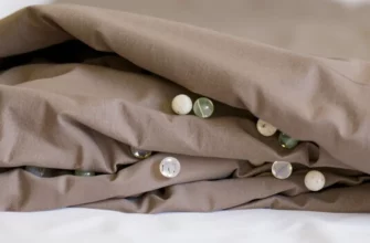 A close-up, photorealistic image of a weighted blanket with glass beads, showing the beads' texture and the blanket's fabric. The blanket is neatly folded and resting on a clean, white surface. Focus on the details of the beads and the fabric weave.