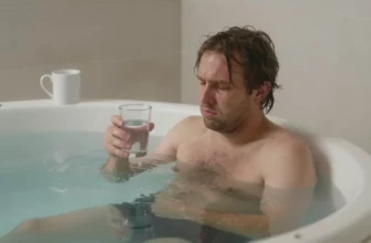 A person with disheveled hair and a slightly pale complexion, looking relieved, stepping into a crystal-clear ice-filled plunge pool surrounded by frosty steam. The scene includes subtle hints of a morning setting, like a dimly lit bathroom with a towel rack and a glass of water on a nearby shelf, emphasizing the contrast between the cold water and the hangover relief. The focus is on the refreshing immersion and the scientific, health-oriented atmosphere.