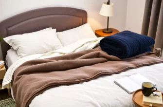 A cozy bedroom scene with a neatly made bed featuring a variety of weighted blankets in different colors and textures. The blankets should be folded and displayed prominently on the bed, with a soft, inviting light illuminating the room. Include a small side table with a cup of tea and a book to suggest relaxation and comfort.