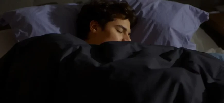 A person sleeping peacefully under a weighted blanket on a bed. The room is dimly lit, suggesting nighttime. Focus on the person's relaxed posture and the blanket's gentle contours.