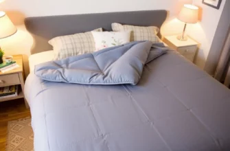 A cozy bedroom scene with a neatly made bed featuring a 9kg weighted blanket in a calming color, such as blue or grey. The blanket should be spread out evenly on the bed, with a soft pillow and a few decorative cushions. The room should have warm lighting, perhaps from a bedside lamp, and a few books or a cup of tea on the nightstand to create a relaxing atmosphere.