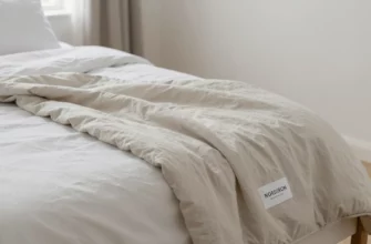 A serene bedroom scene featuring a neatly made bed with a soft, neutral-toned weighted blanket draped over it, accompanied by a small label or tag that reads 'Nordstrom Weighted Blanket' without any text or numbers on the blanket itself, soft natural lighting, minimalistic decor, and a calm atmosphere