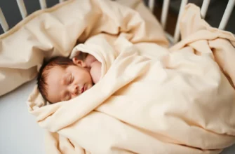 A close-up of a soft, neutral-colored weighted blanket draped over a newborn baby in a crib, with gentle lighting highlighting the texture of the fabric and the baby's peaceful sleep, no text or numbers visible