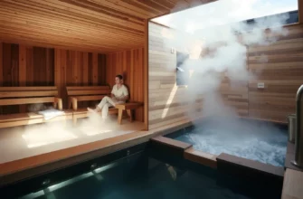 A serene sauna interior with wooden benches, steam rising, and a person relaxing, alongside a modern cold plunge pool with clear water and steam, natural lighting, minimalist design, emphasizing warmth and cool contrast