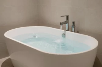 A sleek modern bathroom scene featuring a minimalist cold plunge tub filled with clear icy water, surrounded by smooth stone tiles and soft ambient lighting, conveying a sense of refreshing luxury and wellness
