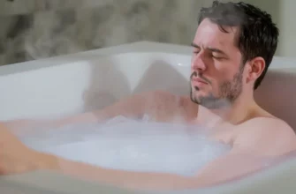 A realistic close-up of a person taking a cold plunge in a modern bathtub filled with icy water, steam rising from the surface, showing a sense of refreshment and determination, with subtle visual cues like faint frost on the edges and condensation on the skin, no text or numbers visible