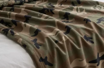 A detailed product showcase of a camo weighted blanket with high-performance fabric texture, displayed on a modern minimalist bed with crisp white linens, soft ambient lighting highlighting the blanket's pattern and material quality, close-up view showing stitching details and fabric weave, natural color palette with earthy camouflage tones, lifestyle photography style