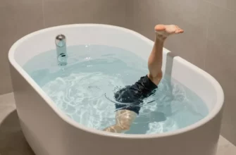 A modern bathroom scene featuring a sleek, minimalist cold plunge tub filled with clear, icy water, surrounded by smooth stone tiles and soft ambient lighting, with a person in athletic wear stepping into the tub, emphasizing the refreshing and therapeutic atmosphere of cold therapy