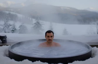 A realistic photo of a person taking a cold plunge in an outdoor icy bathtub, with steam rising from the water, surrounded by natural scenery like snow-covered trees and mountains, conveying a refreshing and invigorating atmosphere