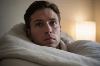 A close-up of a person lying under a weighted blanket, with a subtle expression of discomfort or anxiety visible on their face, surrounded by a calm bedroom environment with soft lighting, no text or numbers visible