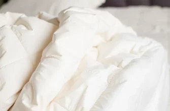 A close-up of a high-quality weighted blanket draped over a cozy bed, showing the fabric texture and subtle stitching, with soft ambient lighting highlighting the luxurious feel, no text or numbers visible