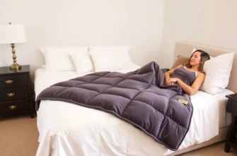 A cozy bedroom scene featuring a 20 lb weighted blanket draped over a comfortable bed, with a relaxed adult sitting on the edge of the bed, looking at the blanket. The blanket should appear plush, inviting, and clearly labeled with a subtle 20 lb tag. The room should have soft lighting and a calm atmosphere.