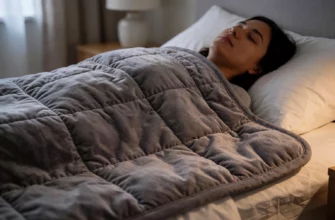 A person lying in bed under a weighted blanket, appearing relaxed with eyes closed, soft ambient bedroom lighting, no visible discomfort or pain, subtle texture of the blanket showing gentle pressure distribution, calm and peaceful atmosphere